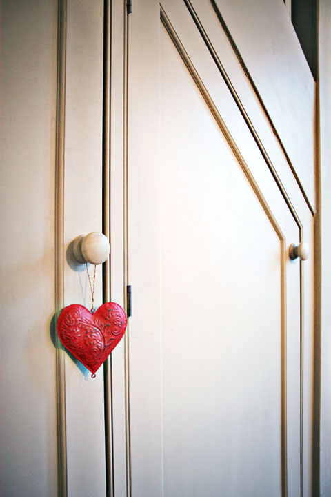 Close-up photo of understairs cupboard door with heart decoration on door handle.